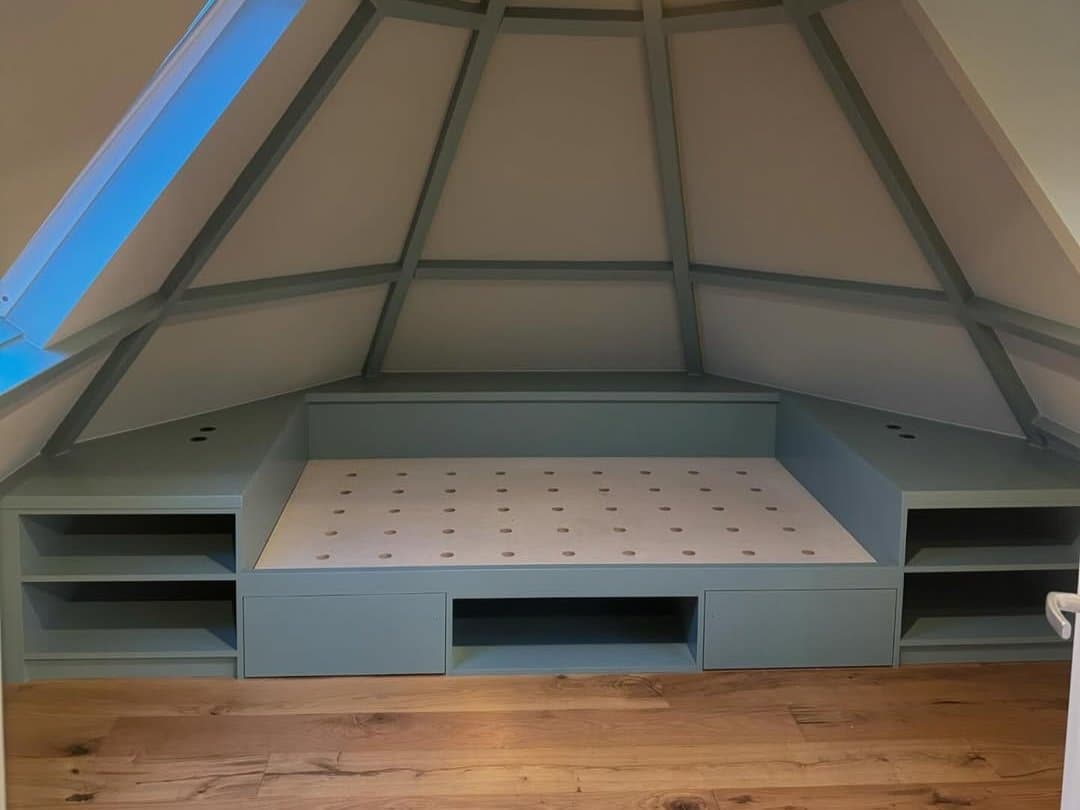 Zolderkamer met in groen geschilderde balken en maatwerk bedmeubel